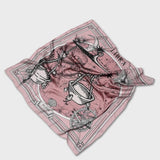Zodiac Scarf for Libra - EVAMAIAZodiac Scarf for Libra made by Plissé. Image of scales. It is on top of a astrological background. Details like a white ecliptic, sun, and moon. The scarf is pink with white details scrunched on plain background.