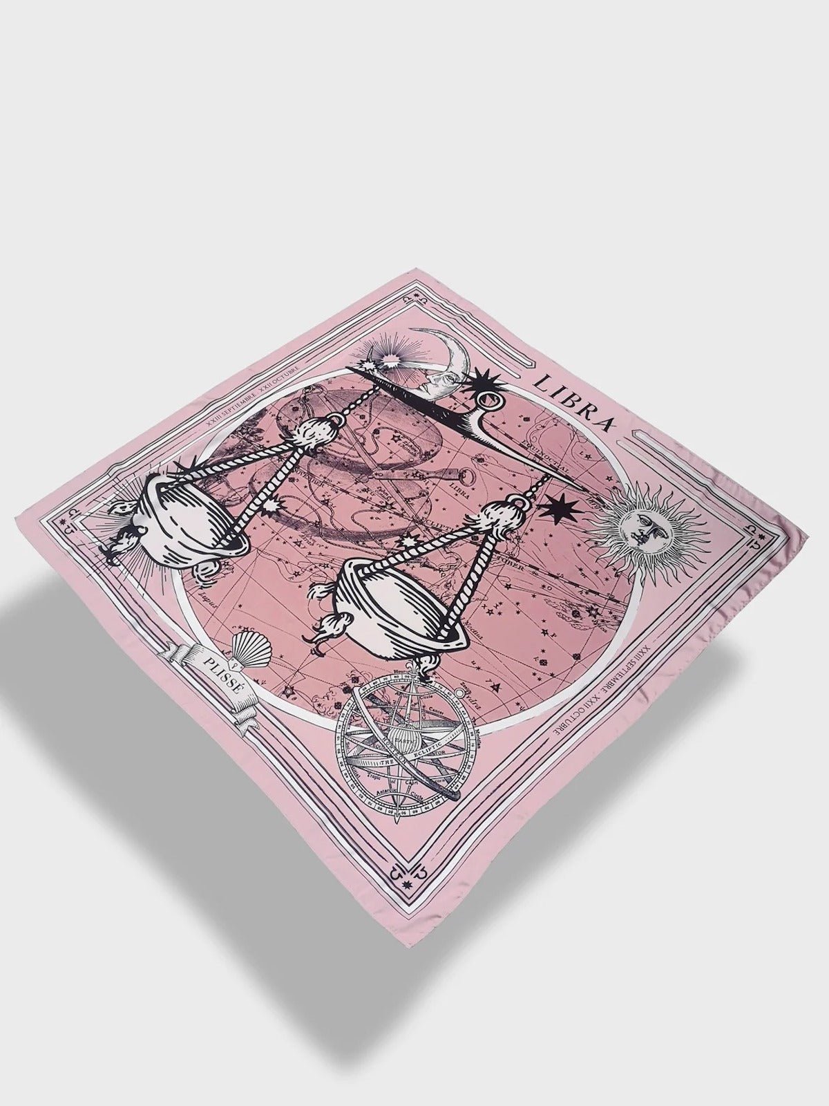 Zodiac Scarf for Libra made by Plissé. Image of scales. It is on top of a astrological background. Details like a white ecliptic, sun, and moon. The scarf is pink with white details floating on plain background.