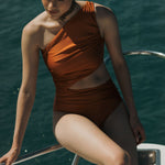 Orange one-shoulder swimsuit with rouching and side cut. 
