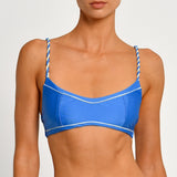 Blue bikini top with white trim and braided straps on a plain background.