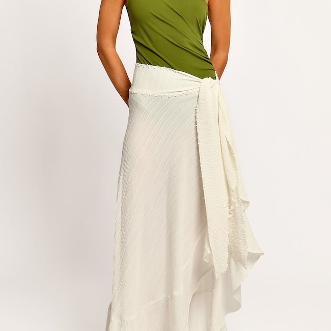 Woman wearing a green top and white skirt on a white background.