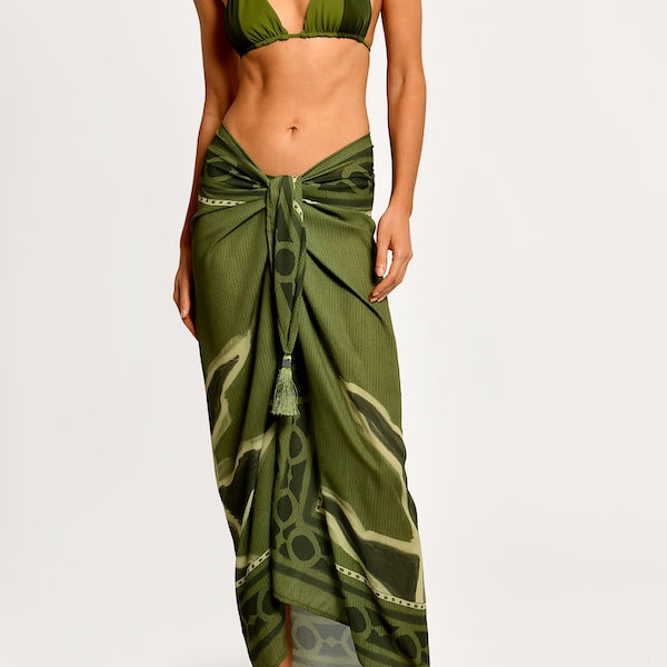 Woman wearing a green bikini with a matching sarong on a white background.