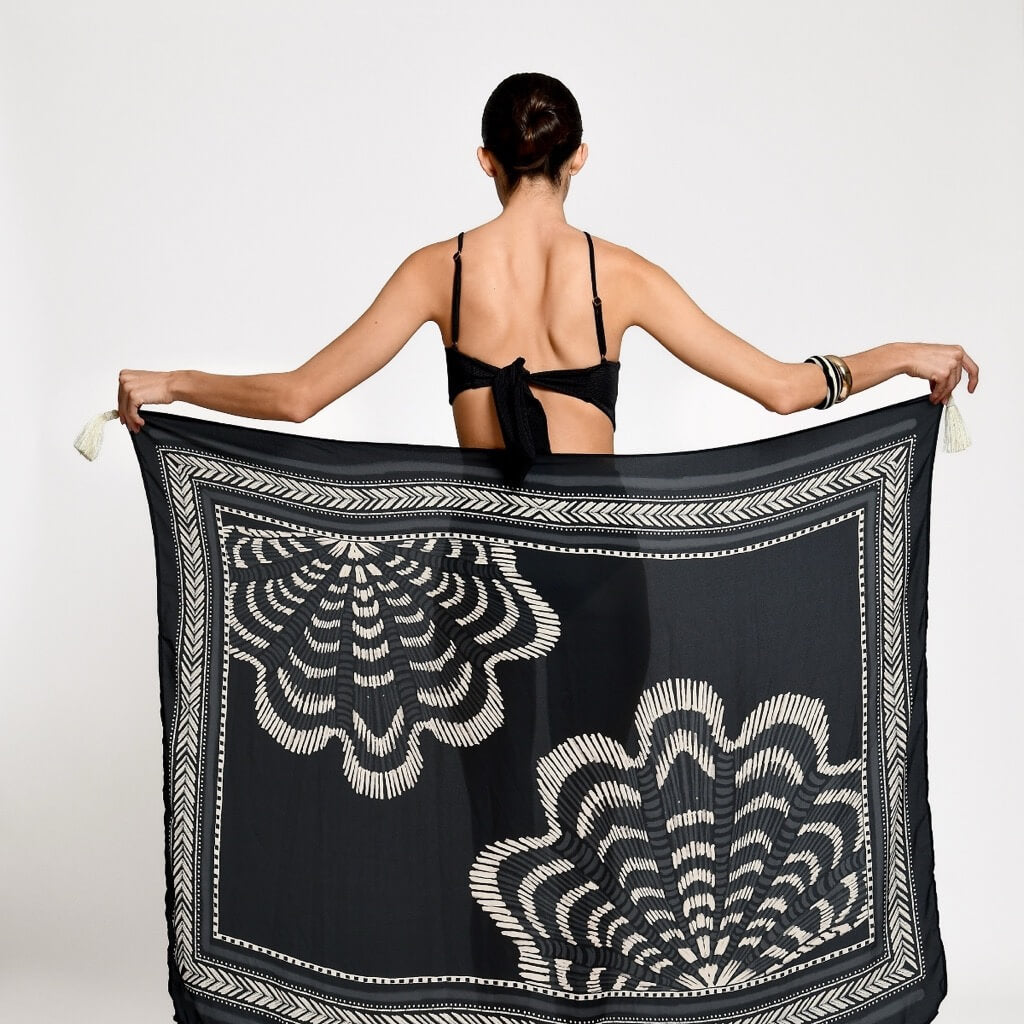 Woman holding a black and white patterned scarf.