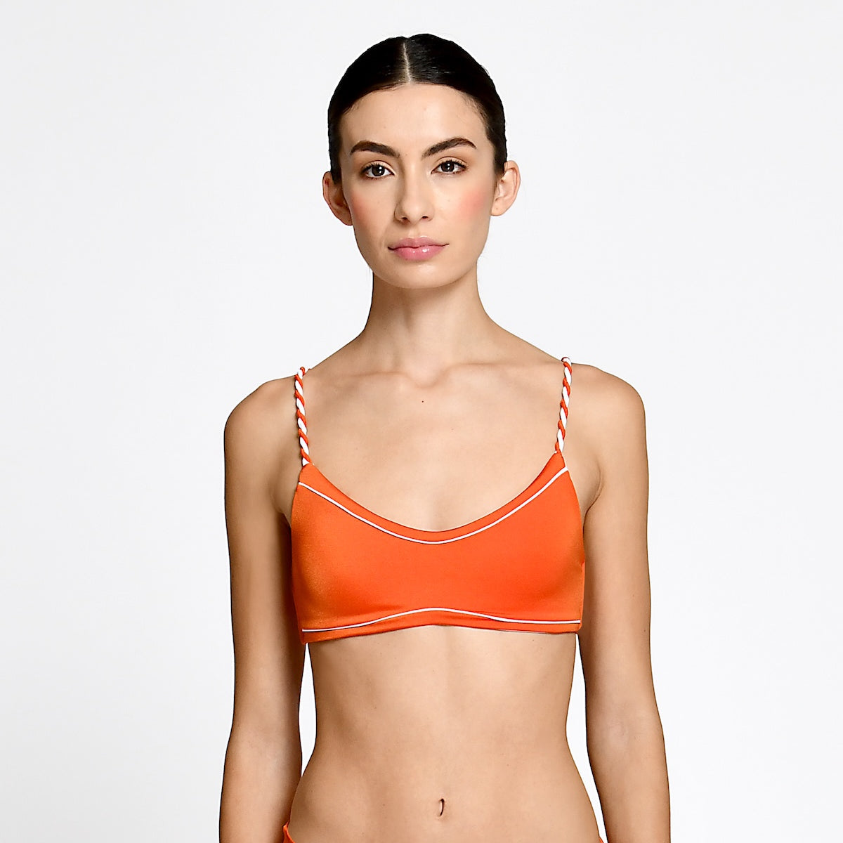 Woman wearing an orange bikini top with thin straps on a white background