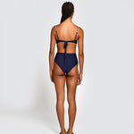 Woman wearing a navy blue bikini with thin straps and high waisted bottoms on a white background