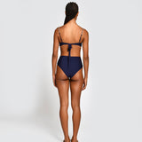 Woman wearing a navy blue bikini with thin straps and high waisted bottoms on a white background