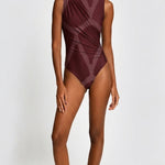 A model wearing a sleeveless, high-neck one-piece swimsuit in a deep burgundy color with a tonal geometric pattern, set against a plain light gray background.