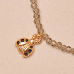 Close-up of a gold necklace with a ladybug charm on a beige background