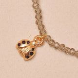 Close-up of a gold necklace with a ladybug charm on a beige background