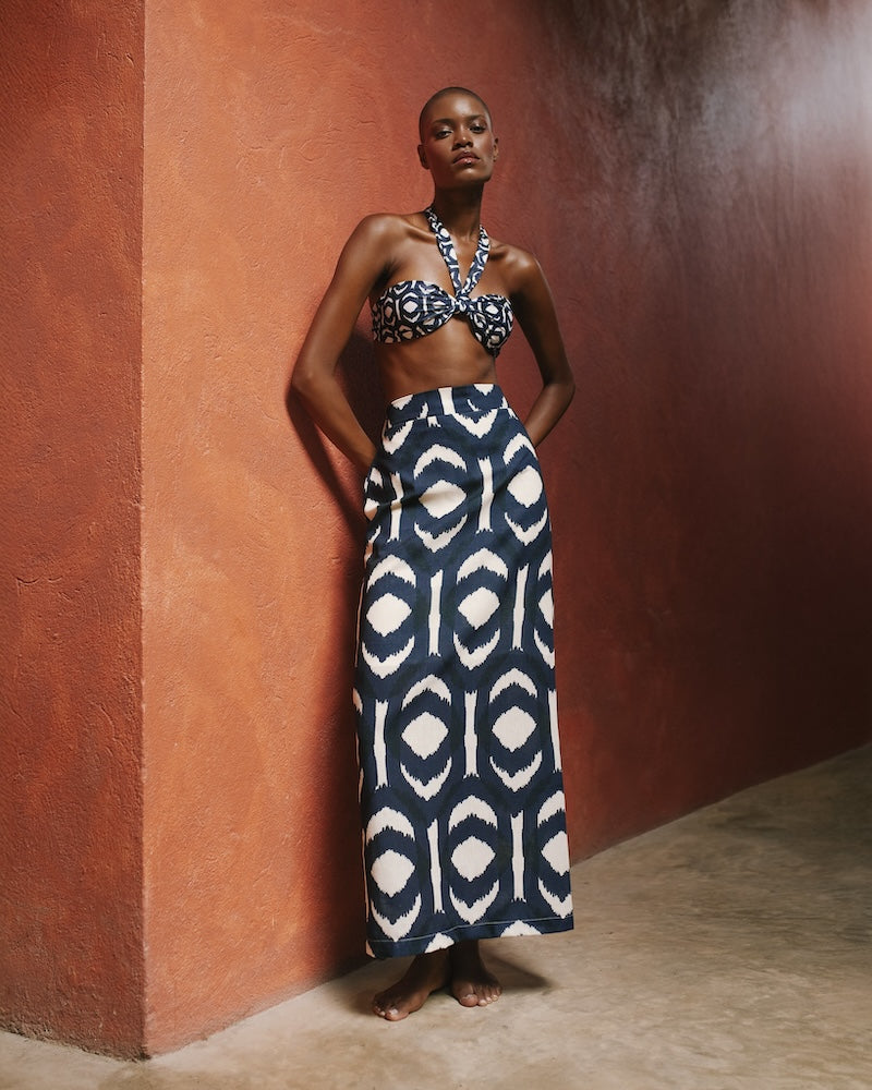 Woman wearing a patterned two-piece outfit against a textured wall.