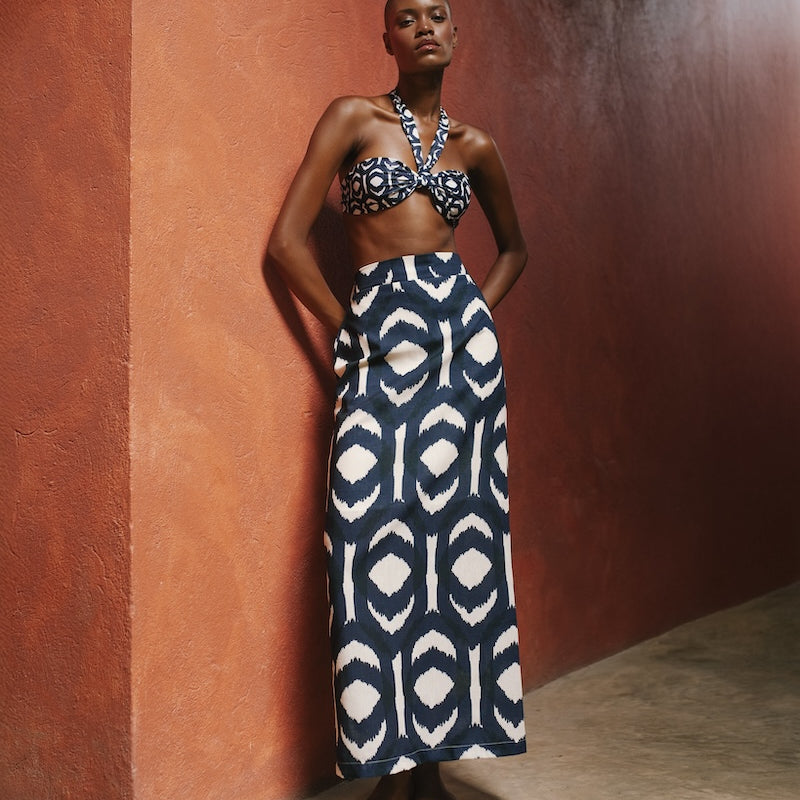 Woman wearing a patterned two-piece outfit against a textured wall.