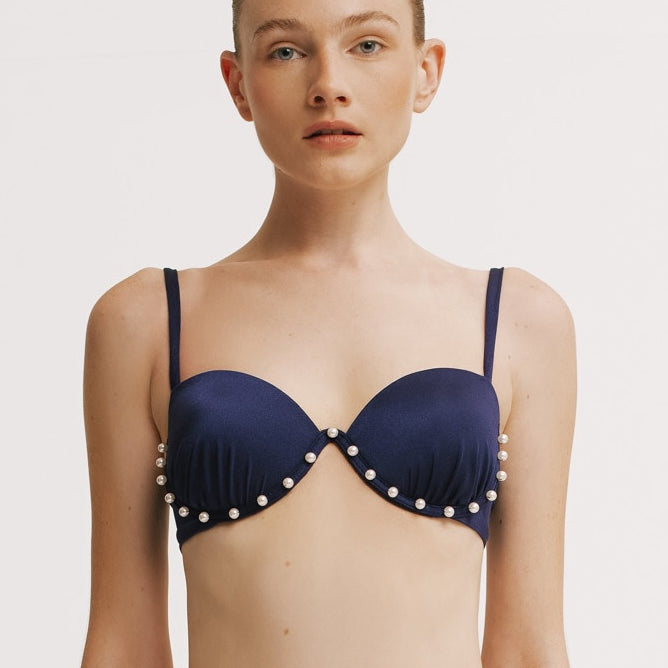 Navy blue bikini top with pearl embellishments on a plain background.