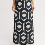 Person wearing a long, patterned skirt on a white background.