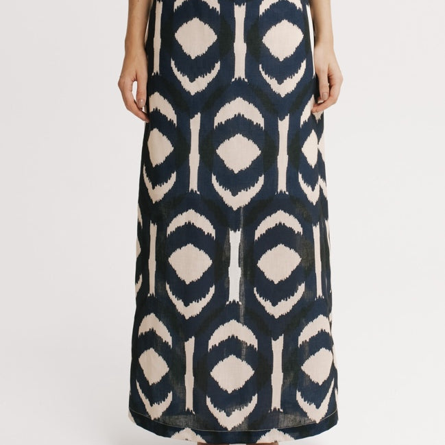 Person wearing a long, patterned skirt on a white background.