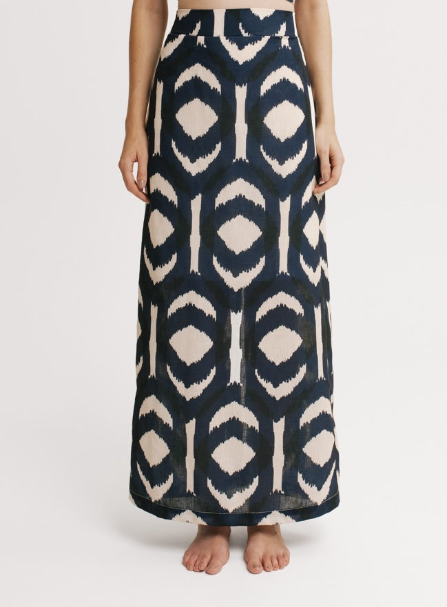 Person wearing a long, patterned skirt on a white background.