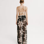 Model wearing a long, patterned dress with thin straps on a white background.