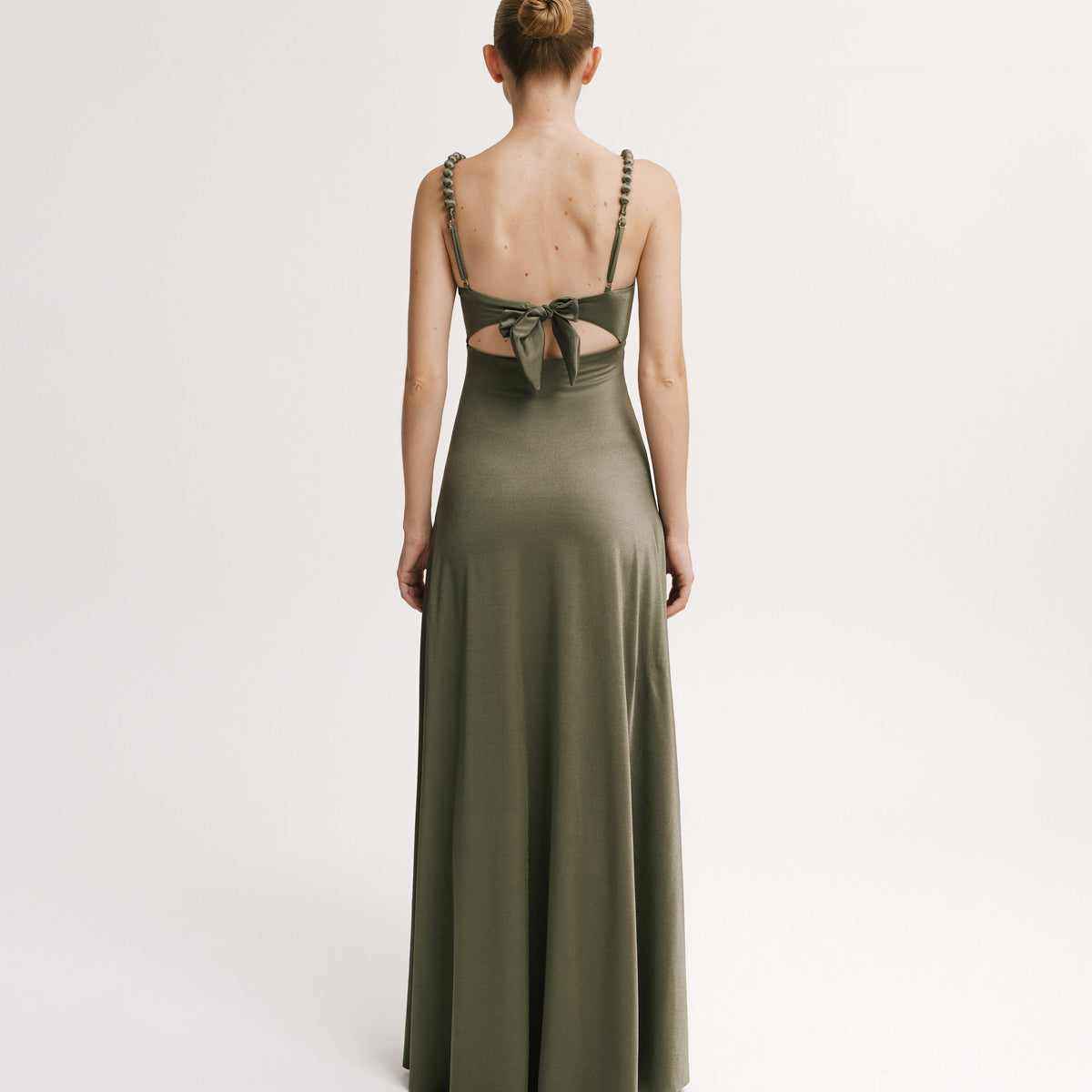 Woman wearing a green evening gown with cut-out back on a white background