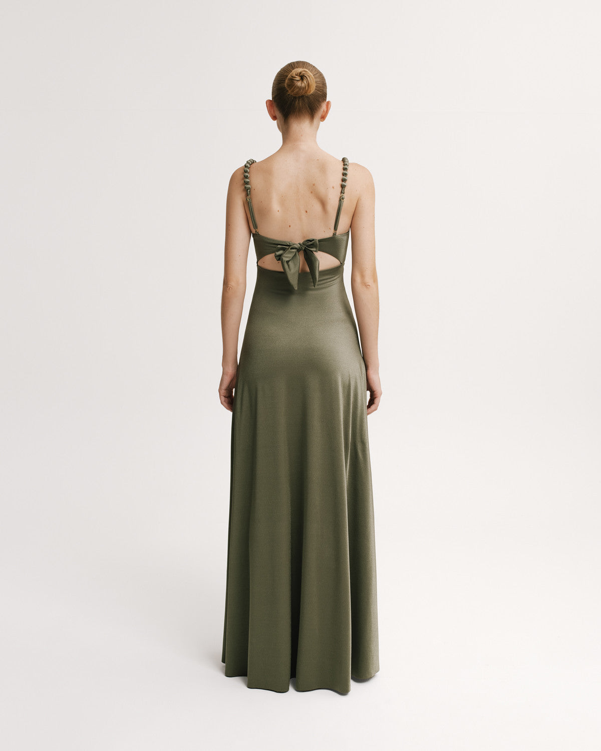 Woman wearing a green evening gown with cut-out back on a white background