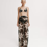 Model wearing a patterned bikini set with a long mesh skirt on a white background