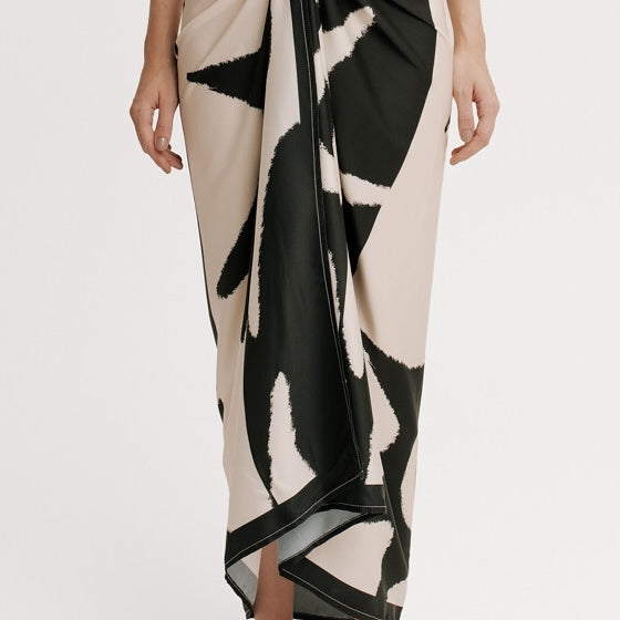 Person wearing a black and white patterned wrap skirt on a plain background