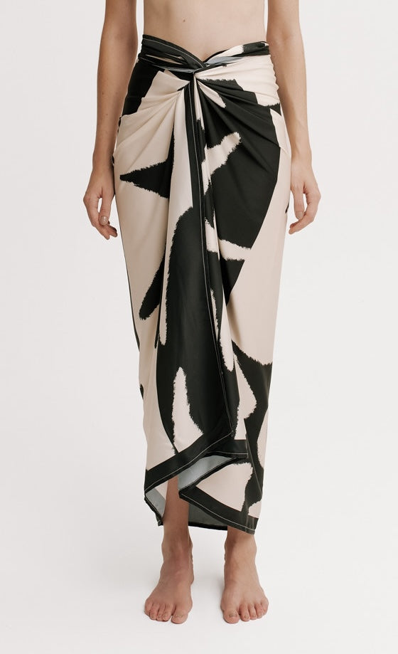 Person wearing a black and white patterned wrap skirt on a plain background