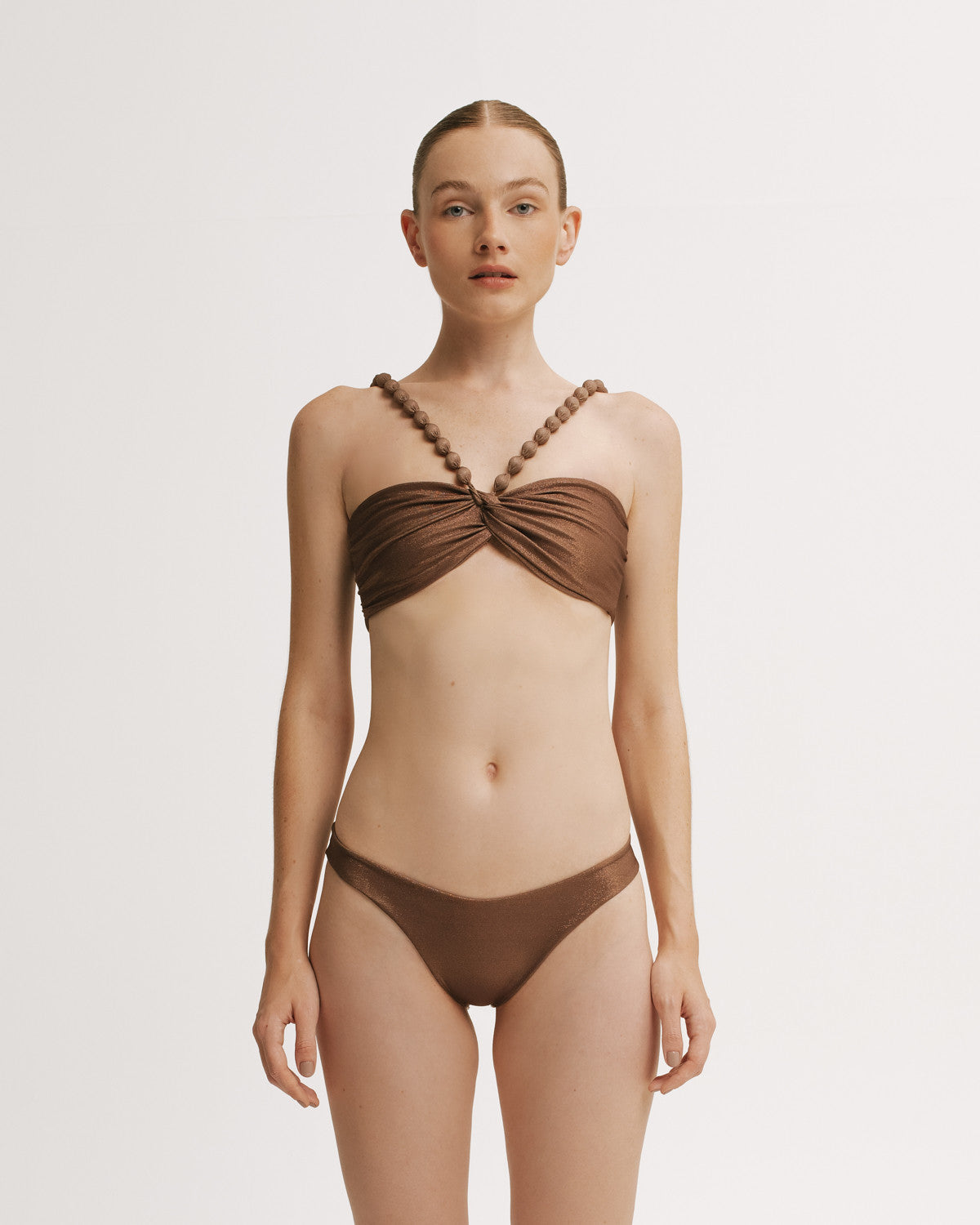 Woman wearing a brown bikini set on a plain background.