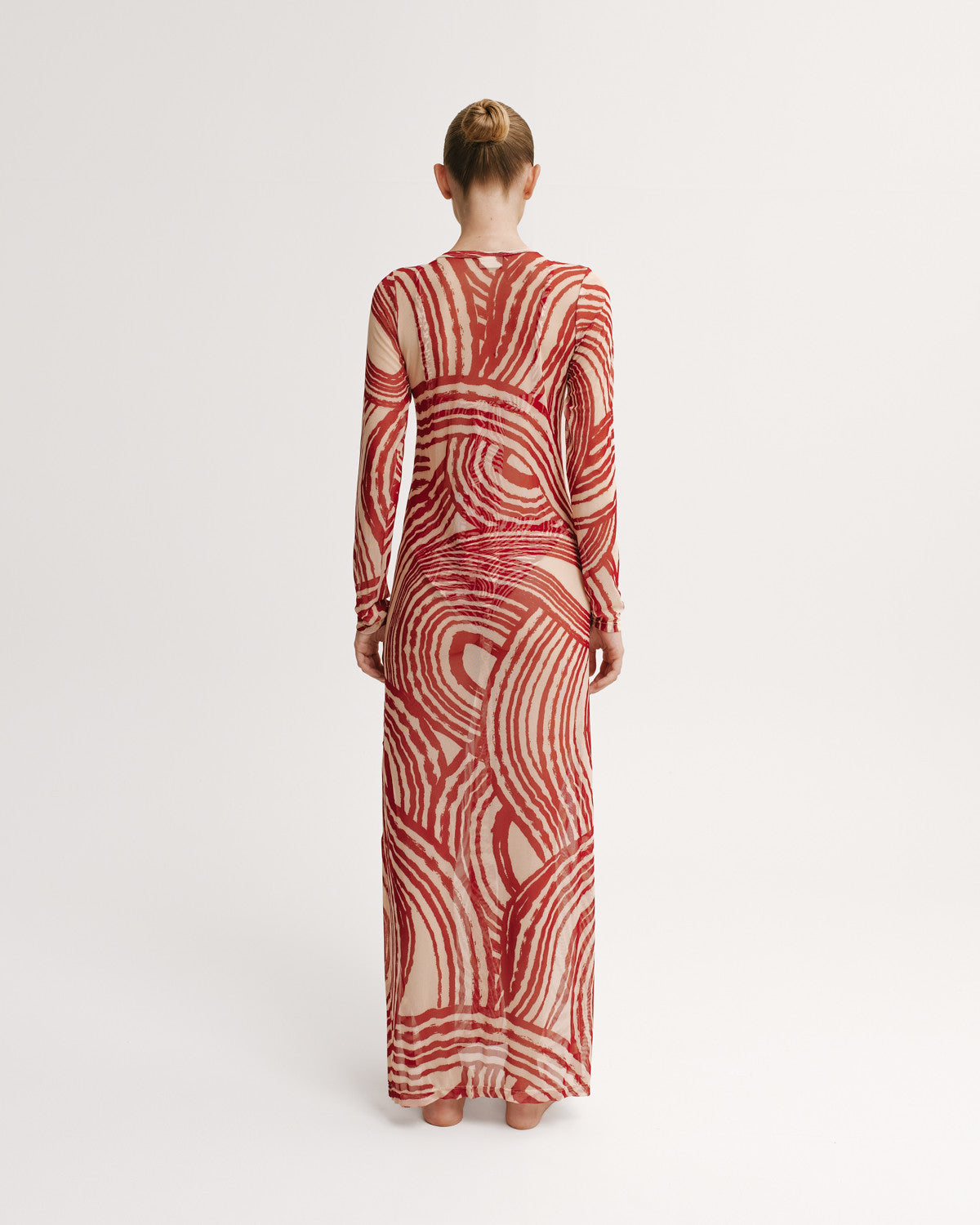 Woman wearing a red and white patterned dress on a white background.