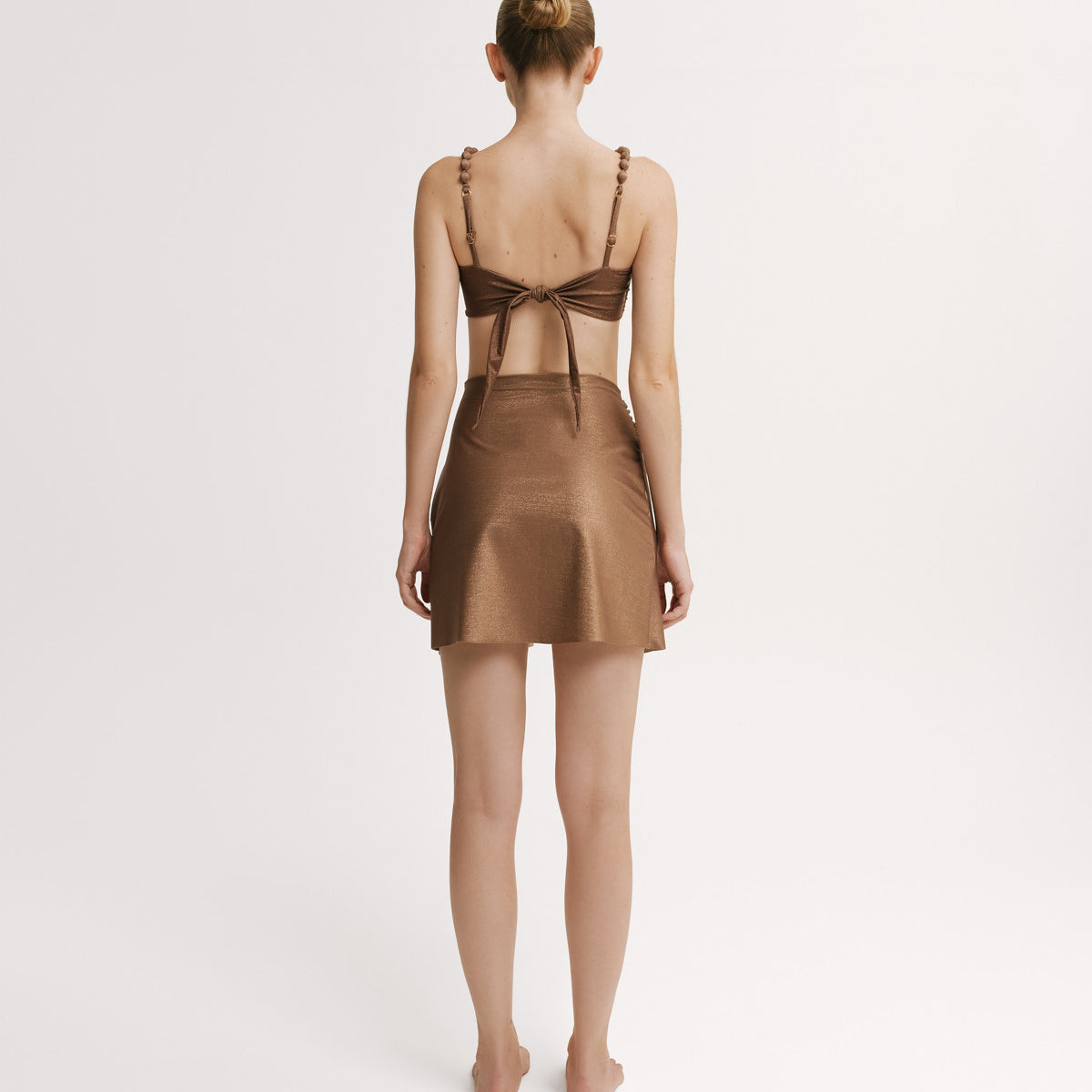 Woman wearing a brown bikini top and matching wrap skirt.