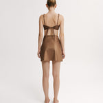 Woman wearing a brown bikini top and matching wrap skirt.