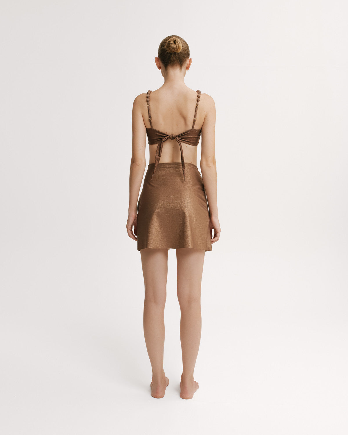 Woman wearing a brown bikini top and matching wrap skirt.