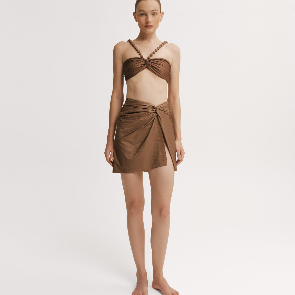 Woman wearing a brown bikini top with a matching wrap skirt. 