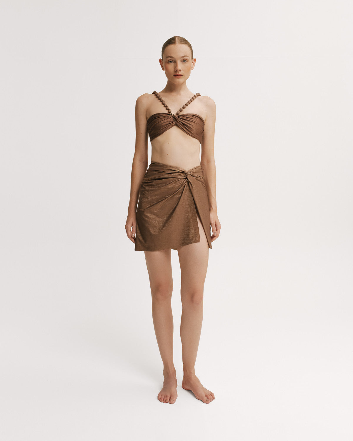 Woman wearing a brown bikini top with a matching wrap skirt. 