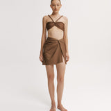 Woman wearing a brown bikini top with a matching wrap skirt. 