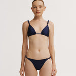 Woman wearing a navy blue bikini on a white background.