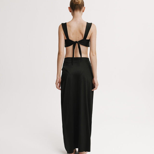 Woman wearing a black dress with open back on a white background