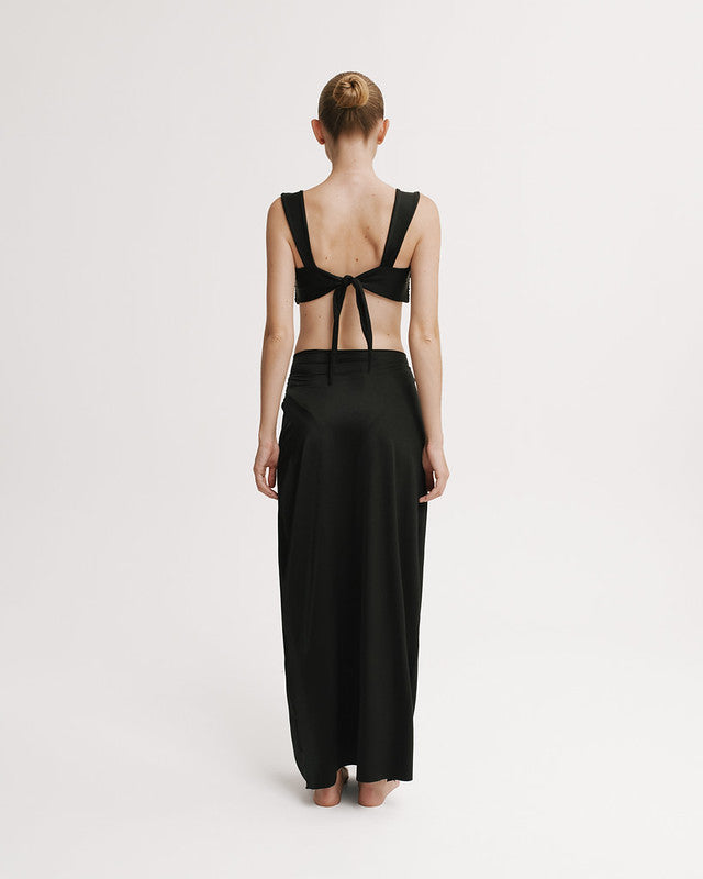 Woman wearing a black dress with open back on a white background