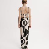 Woman wearing a black and white patterned wrap skirt on a plain background