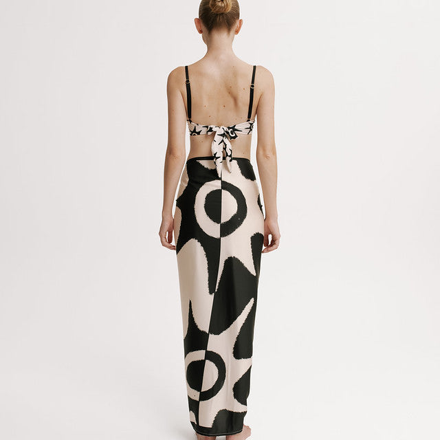 Woman wearing a black and white patterned wrap skirt on a plain background