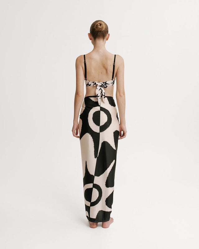 Woman wearing a black and white patterned wrap skirt on a plain background