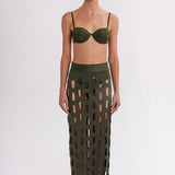 Model wearing a green bikini with cut-out pattern on a white background