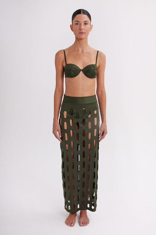 Model wearing a green bikini with cut-out pattern on a white background