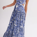 Woman wearing blue and white geometric print halter maxi dress with cutout waist and tiered skirt