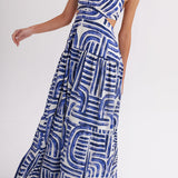 Woman wearing blue and white geometric print halter maxi dress with cutout waist and tiered skirt