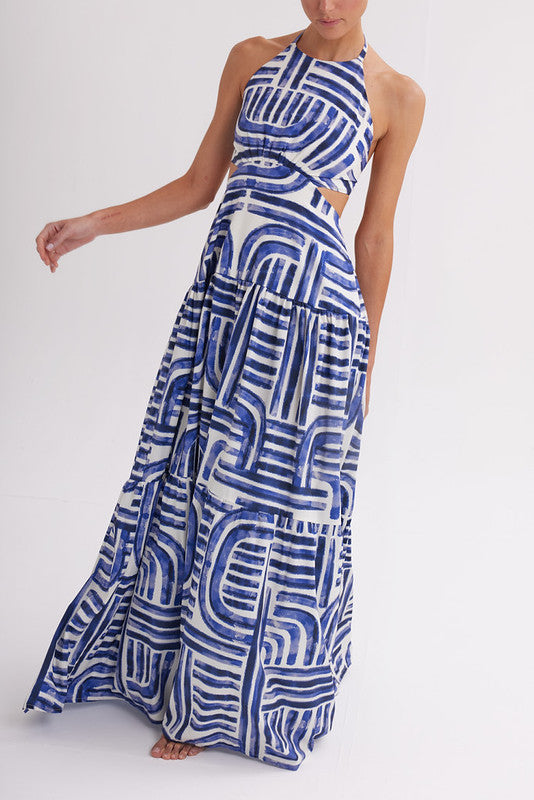 Woman wearing blue and white geometric print halter maxi dress with cutout waist and tiered skirt