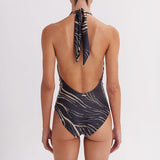 Woman wearing a black and gold patterned swimsuit with a white background