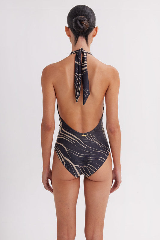 Woman wearing a black and gold patterned swimsuit with a white background