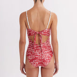 Woman wearing a red swimsuit with white patterns on a plain background