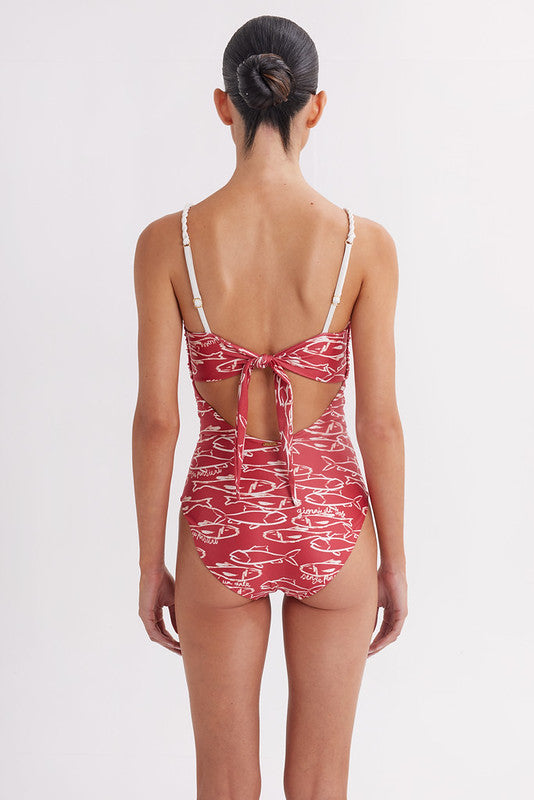 Woman wearing a red swimsuit with white patterns on a plain background
