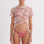 Woman wearing a red and white patterned bikini and top on a white background