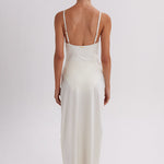 Woman wearing a white slip dress on a plain background. Skirt available at EVAMAIA.